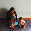 A woman and her two children in their home outside of Danang.  The girl on the floor is nine years old, her brother, in his mother's lap, is ten.