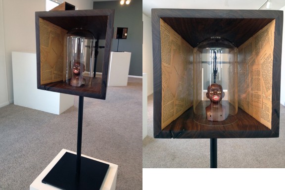 Walnut, steel, antique doll head, bell jar, wooden cross, plastic babydoll, 1908 grammar booklet.