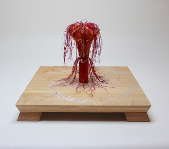 Book sculpture encircled with poetry inscribed in silver on the cutting board.